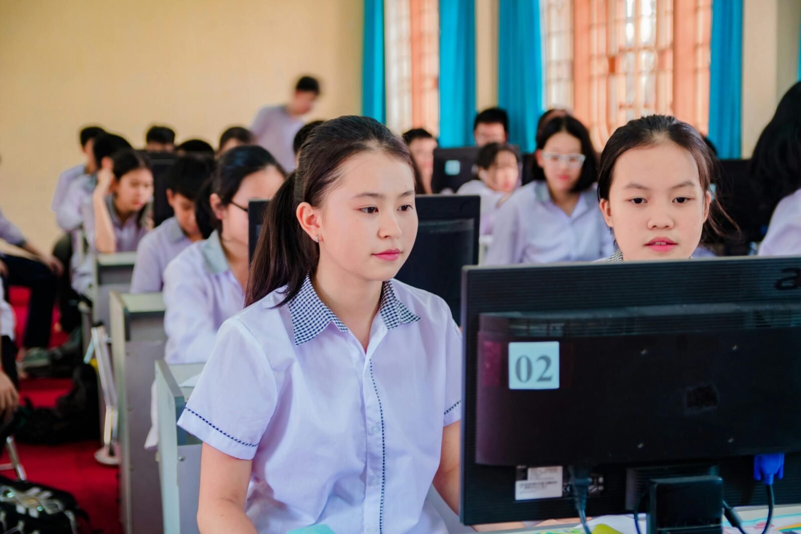 Group of high school students focused on learning in a computer lab setting.