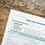 Top view of a credit card application form on rustic wooden background.
