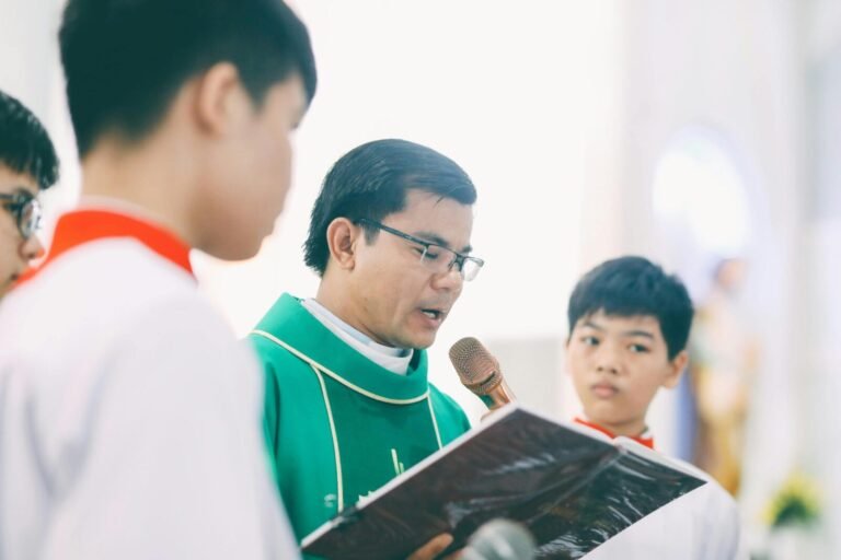A priest recites a holy book during a religious ceremony with altar boys in a church.